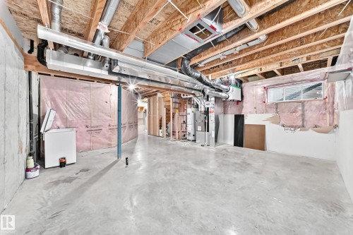 Unfinished basement with exposed ceiling joists, concrete flooring, and visible ductwork - Edmonton, AB 