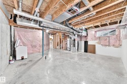 Unfinished basement with exposed ceiling joists, concrete flooring, and visible ductwork - 