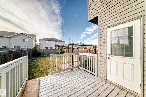 Outdoor deck featuring wood railings and decking, leading to a fenced backyard with a pergola - Edmonton, AB 