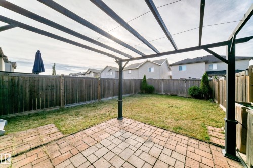 Paved patio with pergola structure, expansive lawn, and full wood fencing - Edmonton, AB 