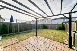 Paved patio with pergola structure, expansive lawn, and full wood fencing - 
