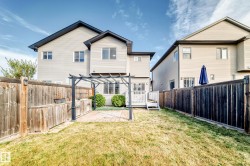 Private backyard with a pergola-covered patio, built-in outdoor kitchen, and a wooden fence - 