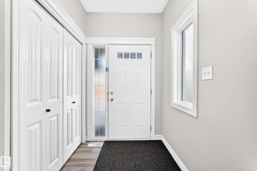 Entryway featuring a white paneled door with transom windows, a sidelight, and wood-finish flooring - Edmonton, AB 