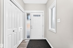Entryway featuring a white paneled door with transom windows, a sidelight, and wood-finish flooring - 