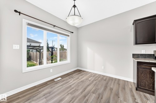 Spacious room featuring wood-finish flooring, a large multi-pane window, and a drum-style ceiling light fixture - Edmonton, AB 