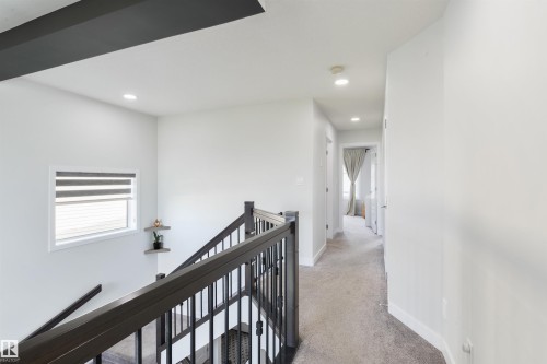 Open staircase with dark wood-finish handrail and wrought iron spindles - 1032 Berg Place, Leduc, AB 