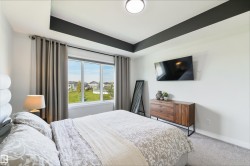Tray ceiling with dark accent, wall-mounted television, large window, and carpeted flooring - 