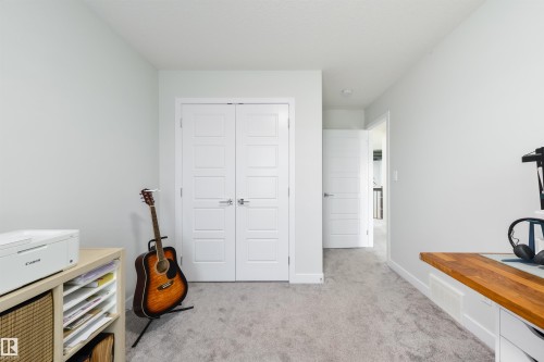 Light gray wall paint, textured gray carpeting, white interior doors with contemporary hardware, and a built-in wooden countertop - 1032 Berg Place, Leduc, AB 