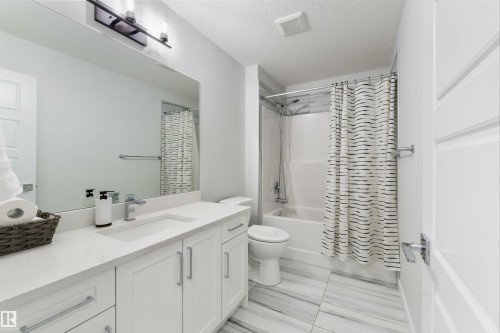 White shaker-style vanity with a light-toned countertop, rectangular undermount sink, and chrome faucet - 1032 Berg Place, Leduc, AB 