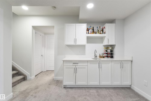 Wet bar with white shaker cabinetry, an integrated sink, and open shelving - 1032 Berg Place, Leduc, AB 