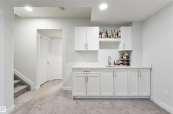 Wet bar with white shaker cabinetry, an integrated sink, and open shelving - 