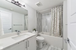 Bathroom featuring a white vanity with an integrated sink, polished chrome faucet, white paneled cabinetry, and a full-width mirror - 