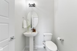 Pedestal sink with an oval mirror, modern wall-mounted light fixture, and tile flooring - 