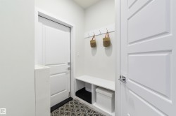 Entryway featuring a built-in bench, wall-mounted coat rack, white paneled doors, and patterned floor tile - 