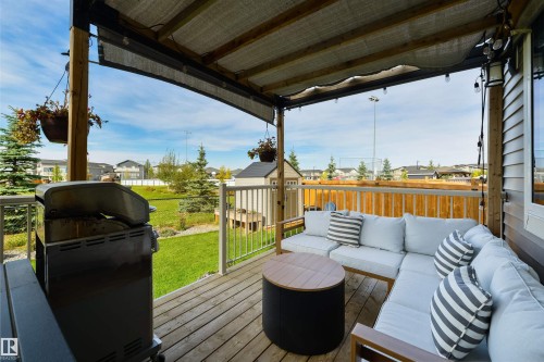 Expansive wood-finish deck with a built-in privacy screen, covered patio, and white metal railings - 1032 Berg Place, Leduc, AB 