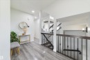 Wood-finish flooring, recessed lighting, white walls, and a staircase with dark wood handrails and black metal spindles - 1032 Berg Place, Leduc, AB 