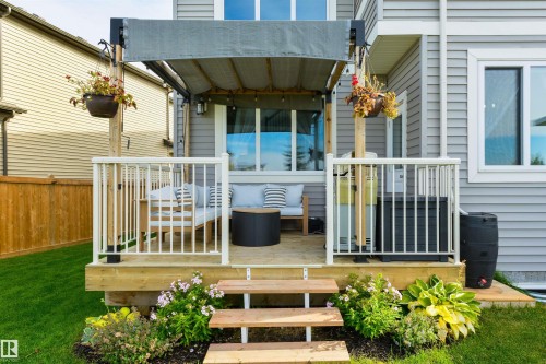 Wood deck with white railing, retractable awning, and wood-finish steps - 1032 Berg Place, Leduc, AB 