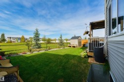 Expansive backyard featuring a manicured lawn, established landscaping, a storage shed, and a wooden deck - 