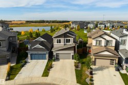 Two-story residence featuring a two-car garage, concrete driveway, and a fenced backyard with a shed - 