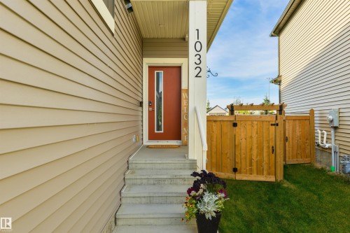 Warm-toned siding exterior with a contrasting red front door - 1032 Berg Place, Leduc, AB 