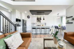 Open-concept living area with wood-finish flooring, a kitchen island with seating, pendant lighting, and a dining area - 