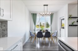 Open dining area with wood-finish flooring, a contemporary chandelier, and a large window - 