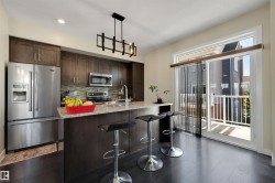 Kitchen featuring dark wood-finish cabinetry, stainless steel appliances, a tile backsplash, light-toned countertops, and dark wood-finish flooring - 