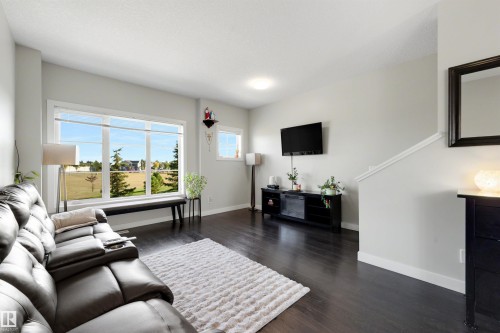 Dark wood-finish flooring, white walls, large multi-pane windows, built-in staircase, and ceiling-mounted lighting - #1 1636 Kerr Rd Nw, Edmonton, AB 