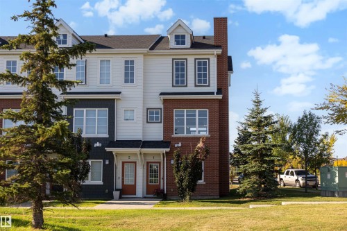 Multi-level townhouse exterior featuring brick and siding finishes, multiple windows, and a prominent chimney - #1 1636 Kerr Rd Nw, Edmonton, AB 