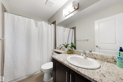 Bathroom featuring a built-in vanity with a light-toned countertop, an undermount sink, and a large mirror - #1 1636 Kerr Rd Nw, Edmonton, AB 