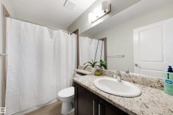 Bathroom featuring a built-in vanity with a light-toned countertop, an undermount sink, and a large mirror - 