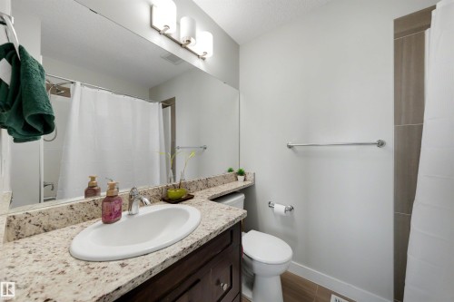 Vanity with an integrated sink, granite-style countertop, and dark wood-finish cabinetry - #1 1636 Kerr Rd Nw, Edmonton, AB 