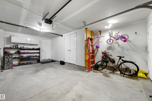 Concrete flooring, overhead garage door system, white walls, built-in storage cabinets, and interior access door - #1 1636 Kerr Rd Nw, Edmonton, AB 