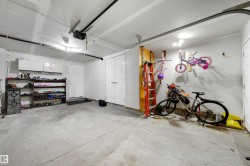 Concrete flooring, overhead garage door system, white walls, built-in storage cabinets, and interior access door - 