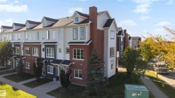 Multi-level townhome architecture featuring brick and siding exteriors, dormer windows, and a gabled roofline - 