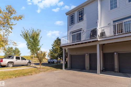 Light-colored horizontal siding, multiple balconies with white railings, and integrated garage doors - #1 1636 Kerr Rd Nw, Edmonton, AB 