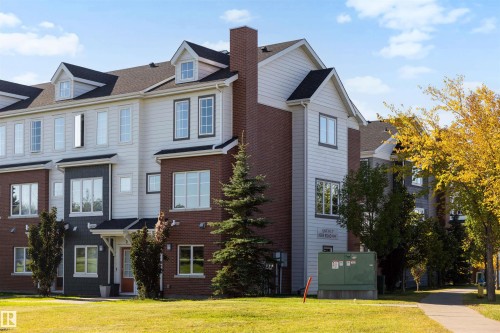 Multi-level townhouse exterior featuring brick and siding finishes, multiple dormer windows, and a prominent brick chimney - #1 1636 Kerr Rd Nw, Edmonton, AB 