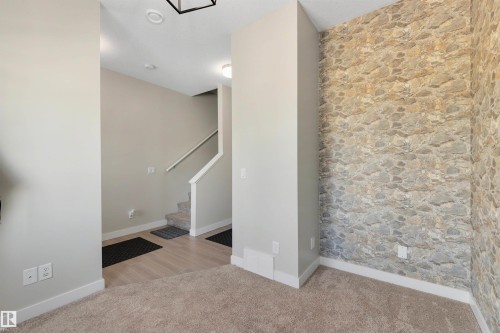 Stone-finish accent wall with carpeted flooring and light wood-finish flooring - #1 1636 Kerr Rd Nw, Edmonton, AB 