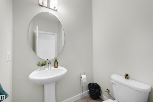 Pedestal sink with a polished chrome faucet and an oval wall mirror - #1 1636 Kerr Rd Nw, Edmonton, AB 