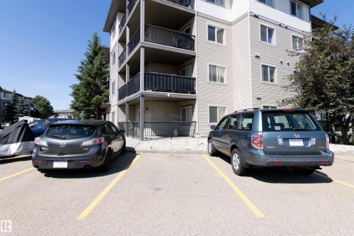 Multi-story apartment building exterior featuring horizontal siding and multiple balconies with black railings - #214 1188 Hyndman Rd Nw, Edmonton, AB 