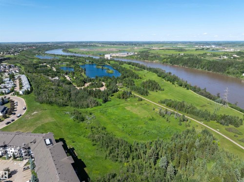Expansive green spaces featuring a winding river, multiple ponds, mature trees, and natural pathways - #214 1188 Hyndman Rd Nw, Edmonton, AB 
