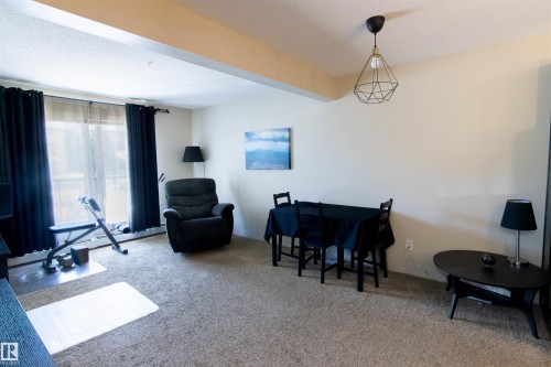 Carpeted living space featuring a sliding glass door with balcony access - #214 1188 Hyndman Rd Nw, Edmonton, AB 
