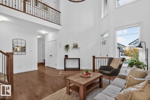 High ceilings with upper transom windows, wood-finish flooring, a decorative front door with clear glass inserts, and an open upper-level railing - 21 Altadena Point(E), Sherwood Park, AB 