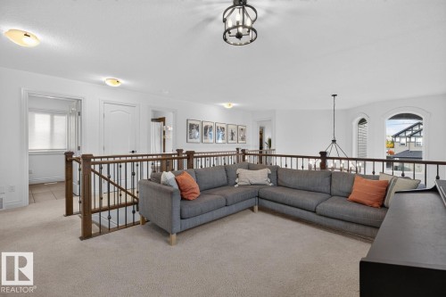 Open-concept upper level featuring neutral carpeting and a wood-finish railing with metal spindles - 21 Altadena Point(E), Sherwood Park, AB 