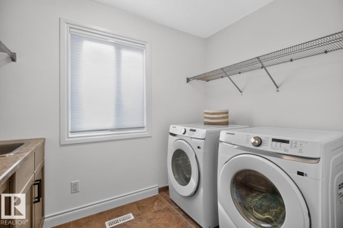 Laundry area with a built-in sink, neutral wood-finish cabinetry, wire shelving, and wood-finish flooring - 21 Altadena Point(E), Sherwood Park, AB 