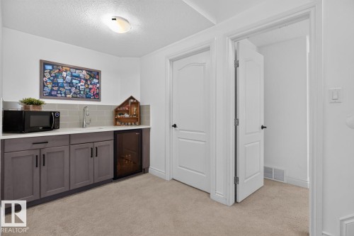 Built-in wet bar featuring gray cabinetry, light-toned countertop, subway tile backsplash, and an under-counter beverage cooler - 21 Altadena Point(E), Sherwood Park, AB 