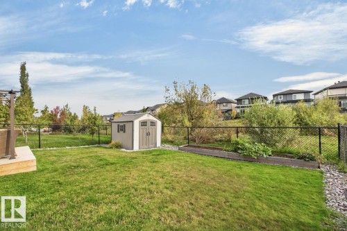 Expansive green space featuring a storage shed, wood-finish raised garden beds, and a chain-link fence - 21 Altadena Point(E), Sherwood Park, AB 