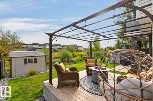 Expansive outdoor deck featuring wood-finish flooring, a metal pergola, and a stone-clad fire pit - 21 Altadena Point(E), Sherwood Park, AB 