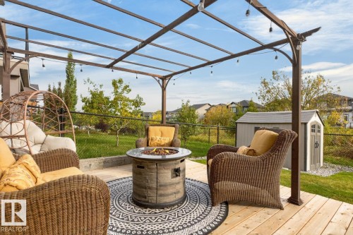 Expansive outdoor deck with a pergola structure, string lighting, and a built-in fire pit - 21 Altadena Point(E), Sherwood Park, AB 