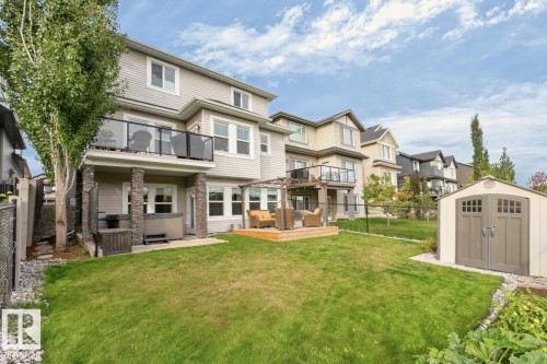 Expansive backyard featuring a manicured lawn, a detached storage shed, a ground-level wood deck with pergola, and a covered patio with a built-in hot tub - 21 Altadena Point(E), Sherwood Park, AB 